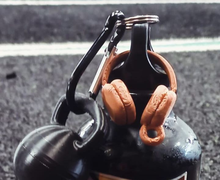 Chaveiros impressos em 3D de kettlebell preto e fone de ouvido cor de cobre presos a uma garrafa