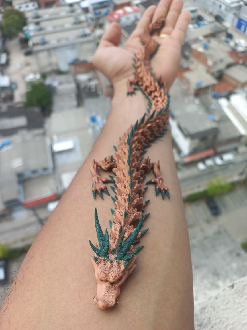 Dragão articulado cor de cobre com espinhos verdes apoiado no braço